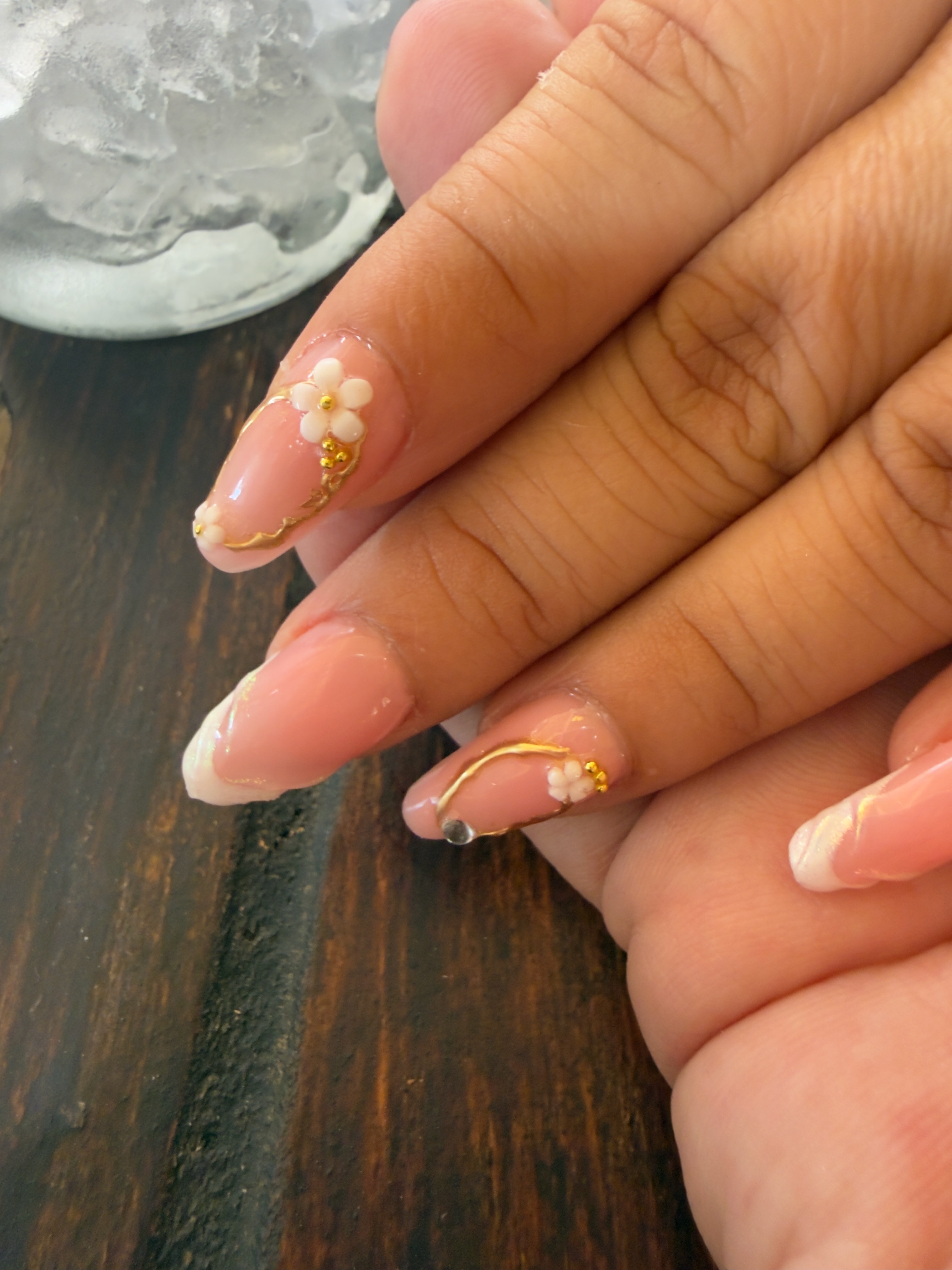 Pink almond-shaped nails with floral and gold detail